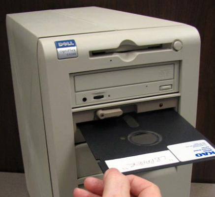 5.25 inch floppy disk being loaded into an ancient PC, which was how PGM desktop was first distributed